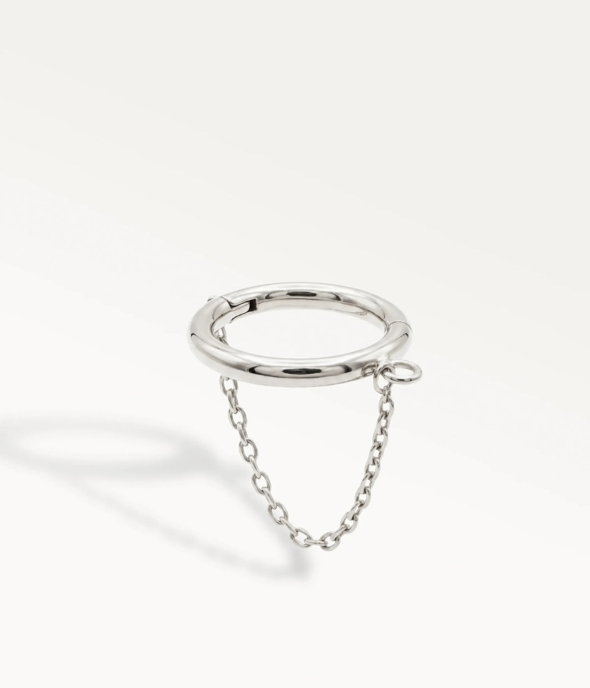 Silver-tone piercing hoop with a fine dangling chain, minimalist, modern ear jewellery in a silver-tone colour