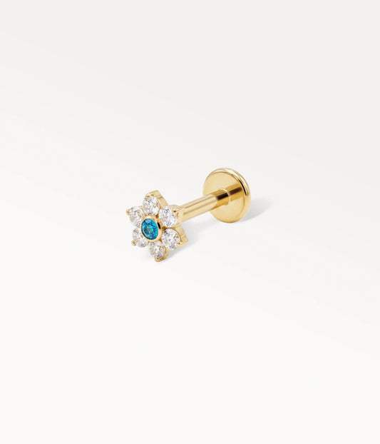 Piercing de cartilage doré en forme de fleur, avec un diamant central bleu et six zircons clairs, vue latérale sur fond blanc.