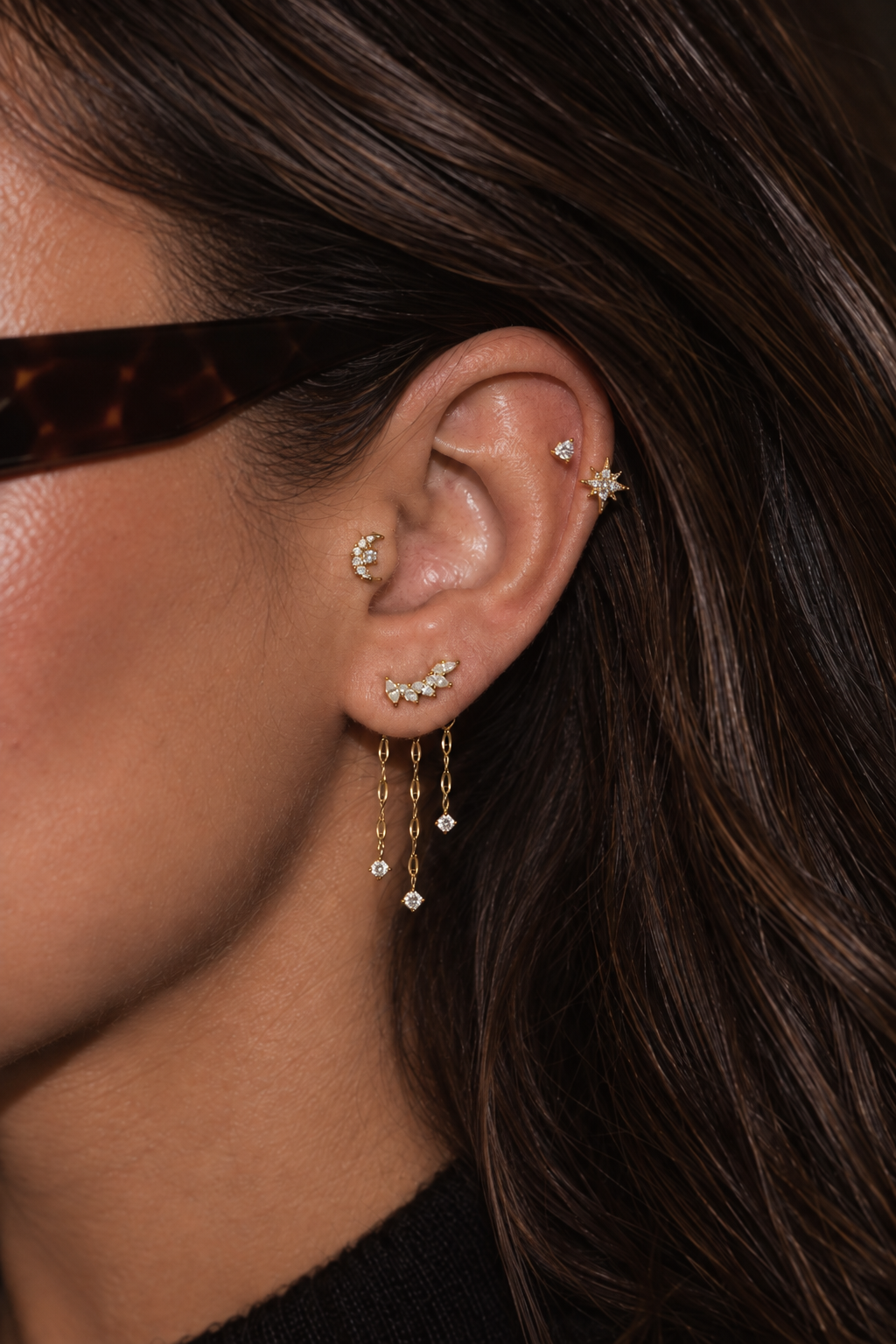 Charlie ear stack being worn, with a moon at the conch, stones on the lobe and three dangling chains.