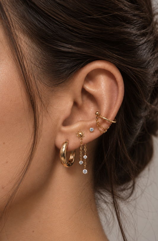 Hélios-koruyhdistelmä, jossa on kolme korua korvalehdessä, ketjuja ja kullanvärinen ear cuff.