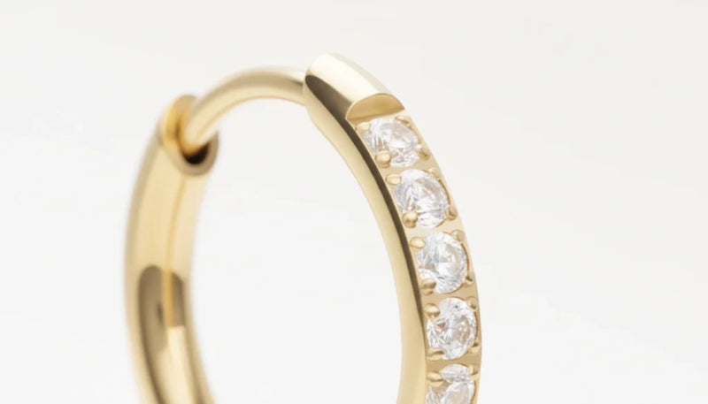 Boucle d’oreille anneau doré sertie de strass scintillants, vue en gros plan détaillée