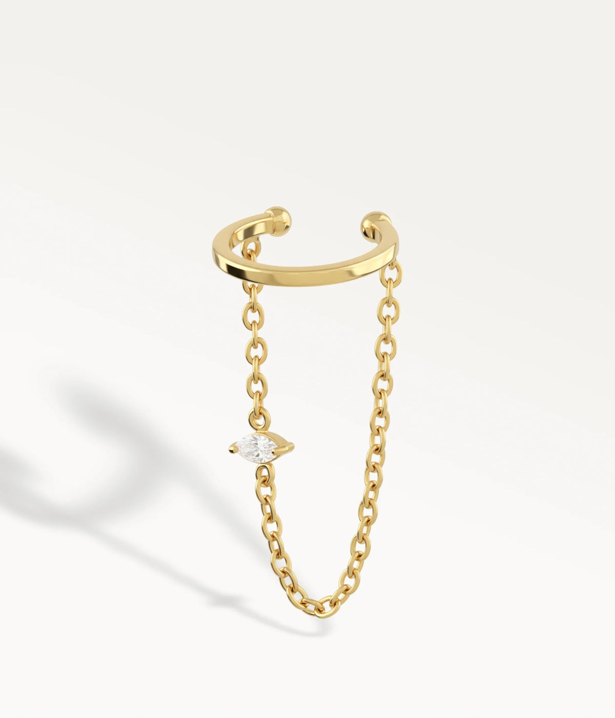 Guldfärgad Lia-ear cuff, öppen ring med hängande kedja och liten sten.