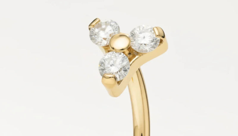 Gros plan sur piercing banane en or décoré de trois zircons étincelants