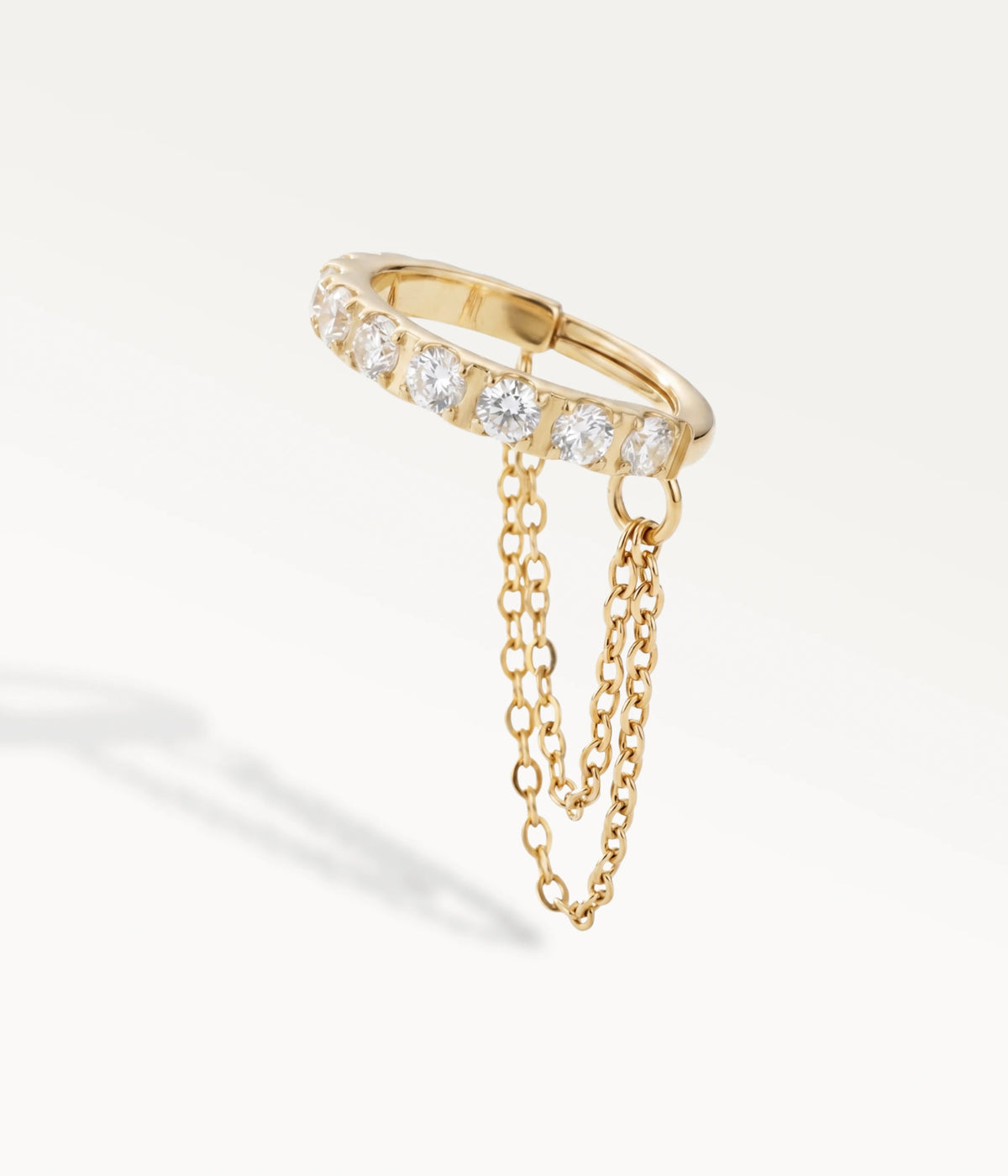 Aro Tessy en color dorado engastado con piedras, con dos finas cadenas colgantes, vista lateral.