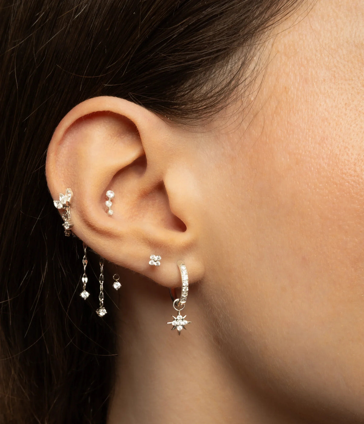 Combinazione color argento indossata con pietre al conch, catene e orecchino a cerchio con stella al lobo.