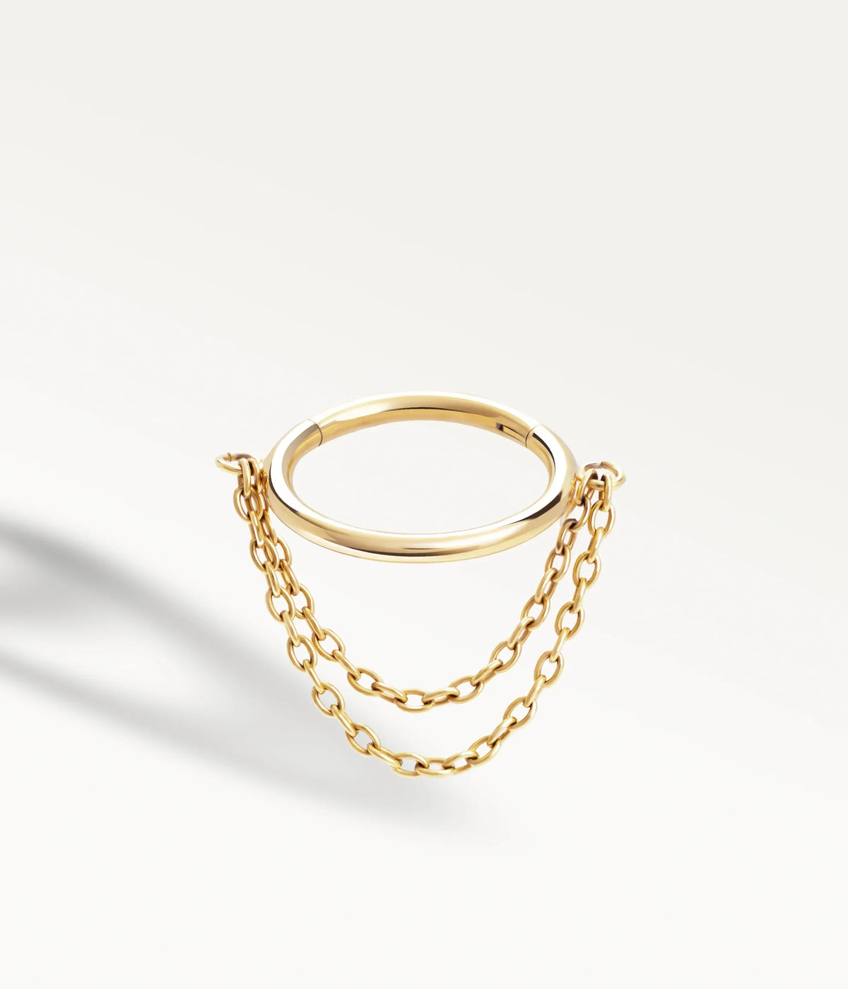 Gold-tone Élyra hoop with two fine hanging chains, three-quarter view.