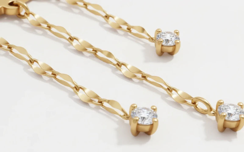 Nahaufnahme einer goldfarbenen Ohrringkette aus Titan mit gefassten Zirkonia