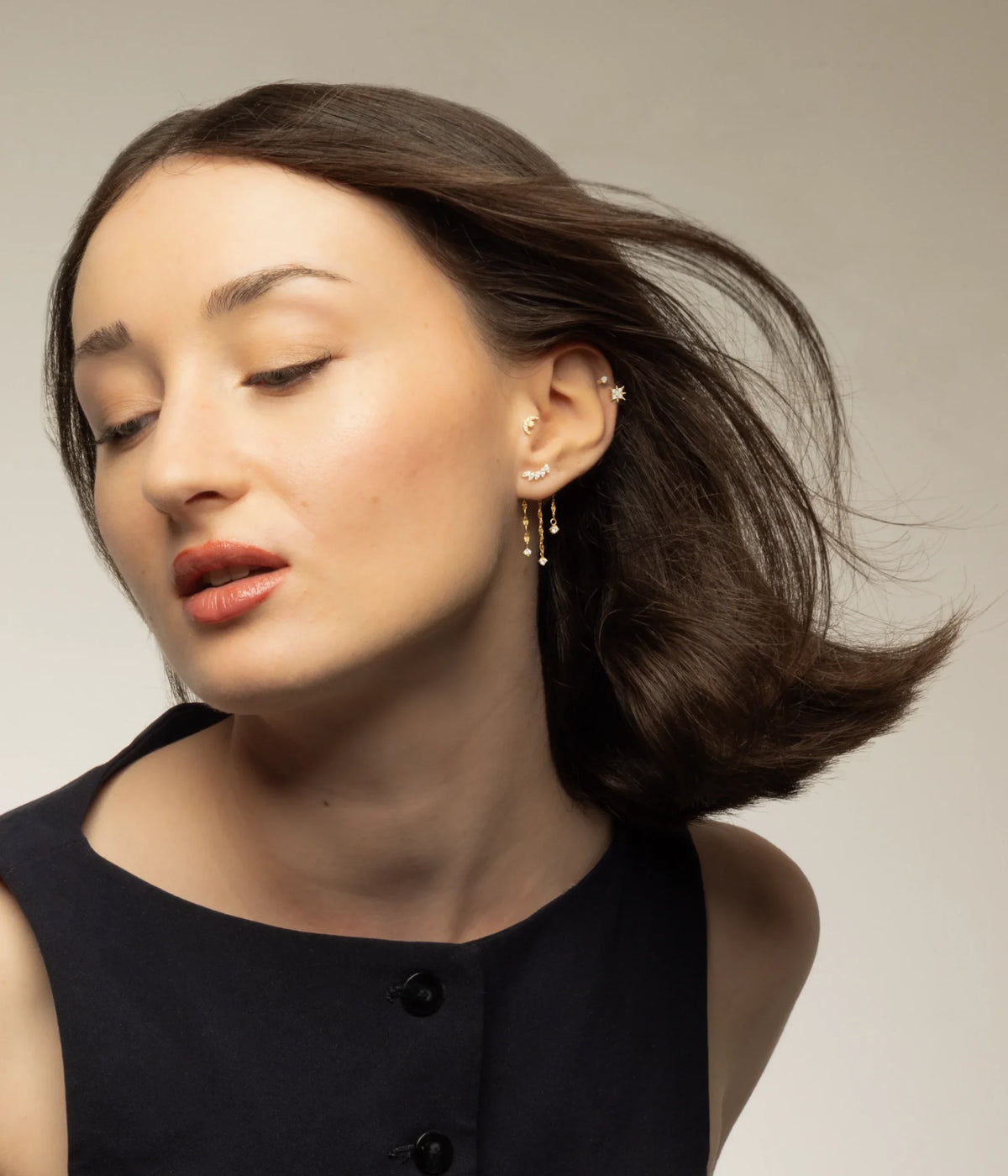 Portrait avec petites créoles à pendentifs et bijoux dorés portés à l’oreille.