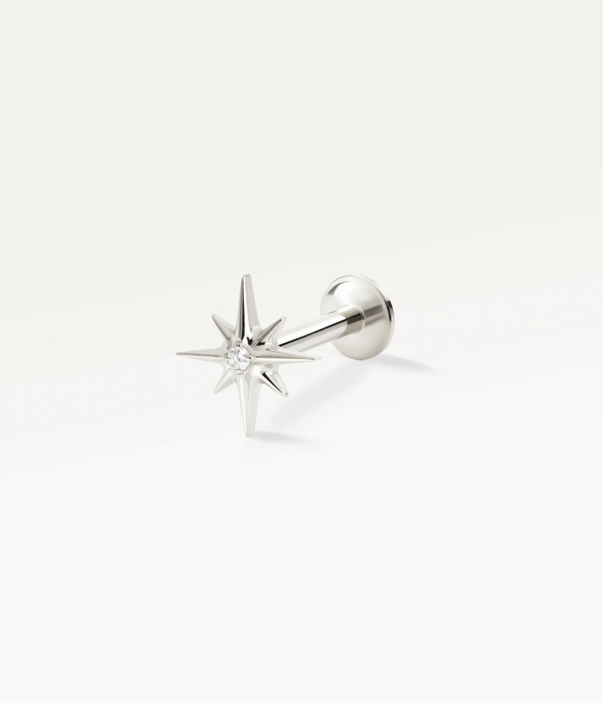 Silver-tone Astrée stud shaped like an eight-pointed star with a central stone, side view.