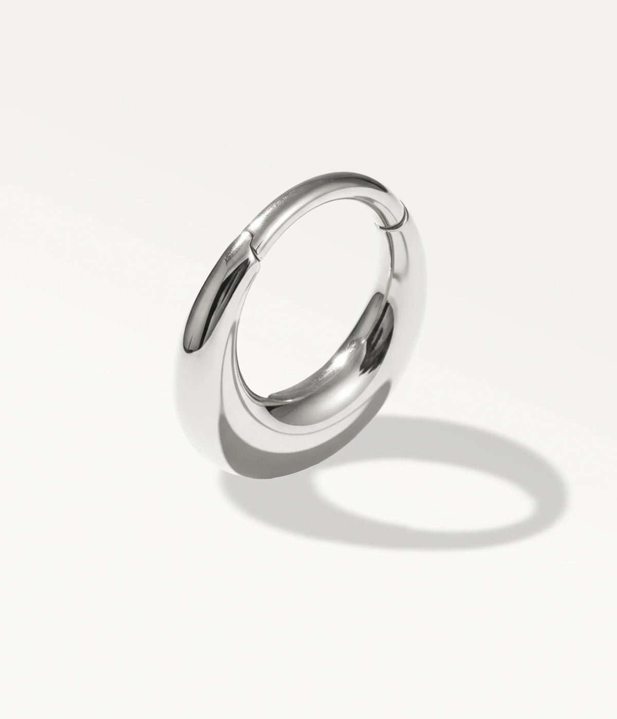 Smooth domed silver-tone Halo hoop, angled view with its shadow.