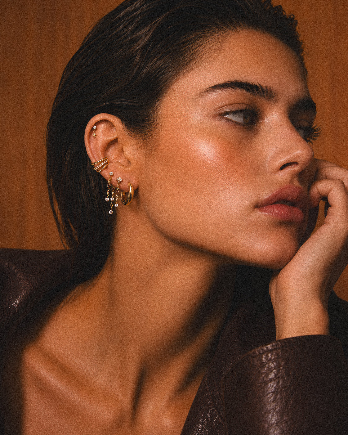 Portrait de profil avec petits bijoux dorés et chaînes portés à l’oreille.