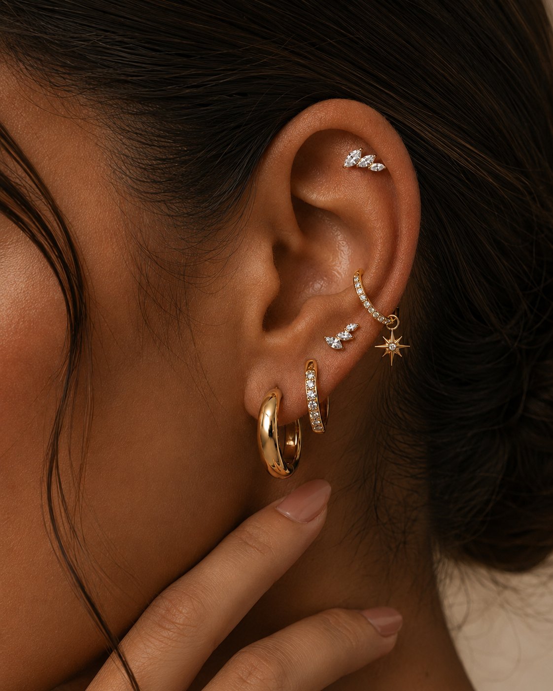 Brooklyn ear stack being worn, with gold-tone hoops, a star pendant and marquise stones at the helix.