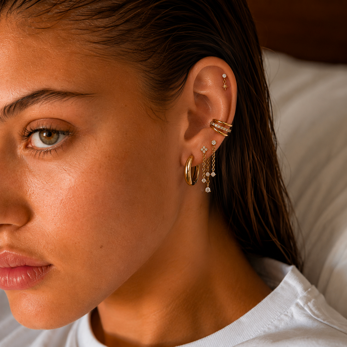 Portrait avec accumulation de bijoux dorés, double anneau au conch et chaînes au lobe.