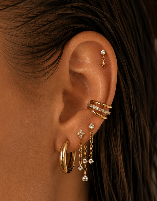 Oreille ornée d’une créole large, de chaînes pendantes et d’un double anneau doré au conch.