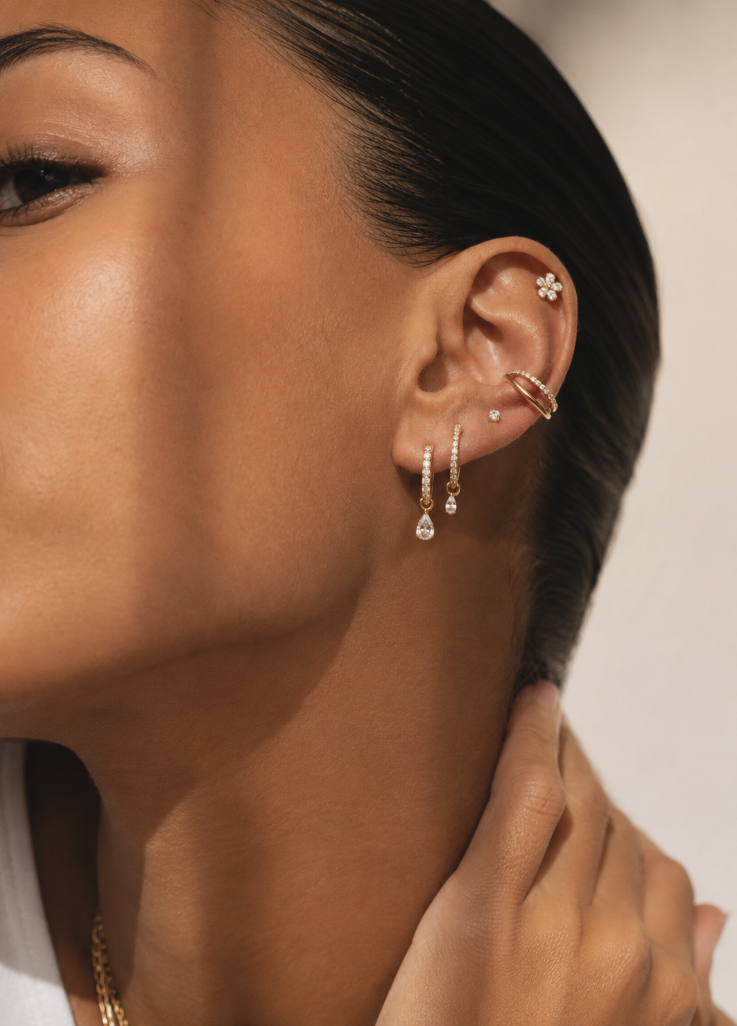 Ear adorned with hoops with pendants, a hoop at the conch and a small stone at the helix.