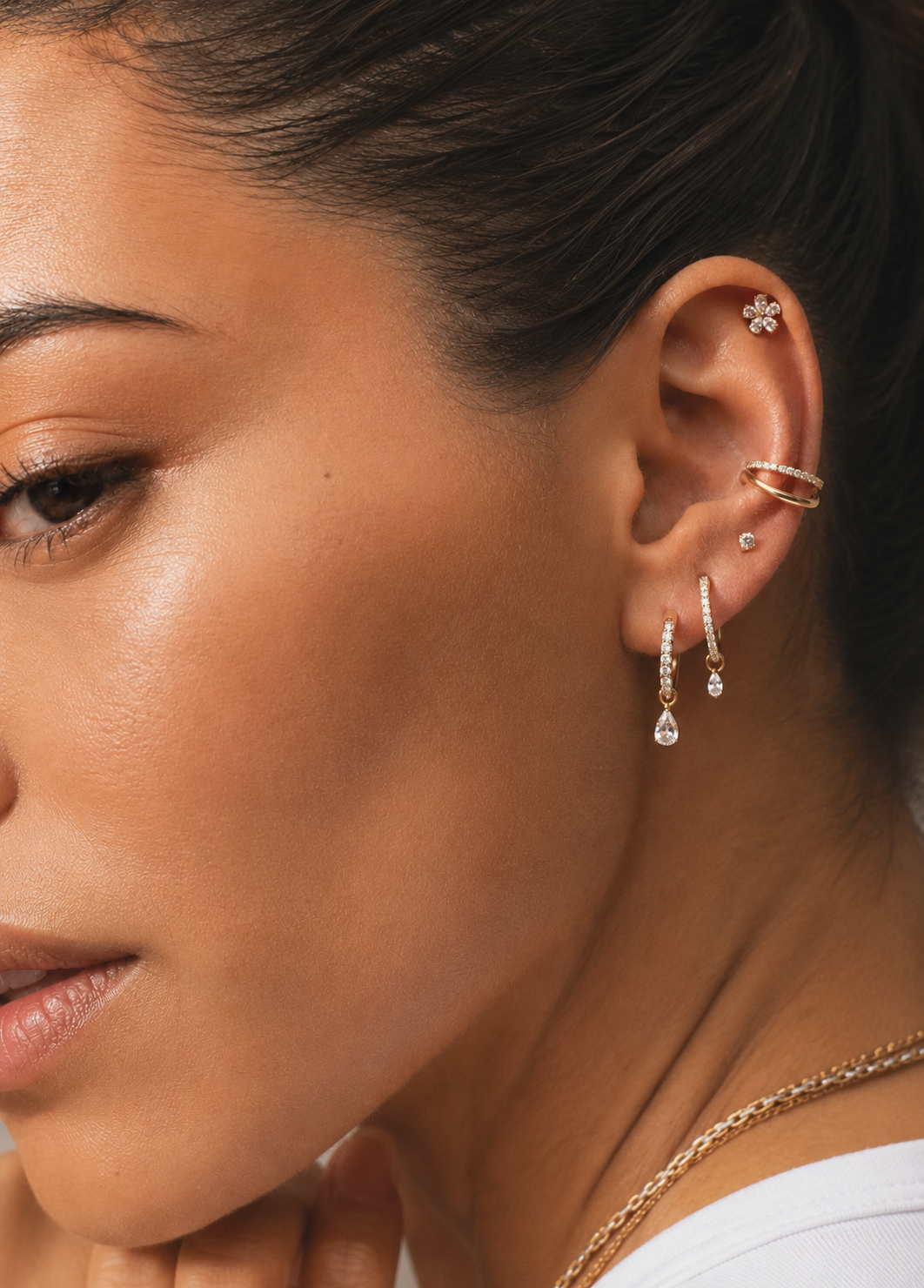 Getragene goldfarbene Kombination mit Creolen mit Tropfenanhängern am Ohrläppchen, Ring am Conch und Blume am Helix.