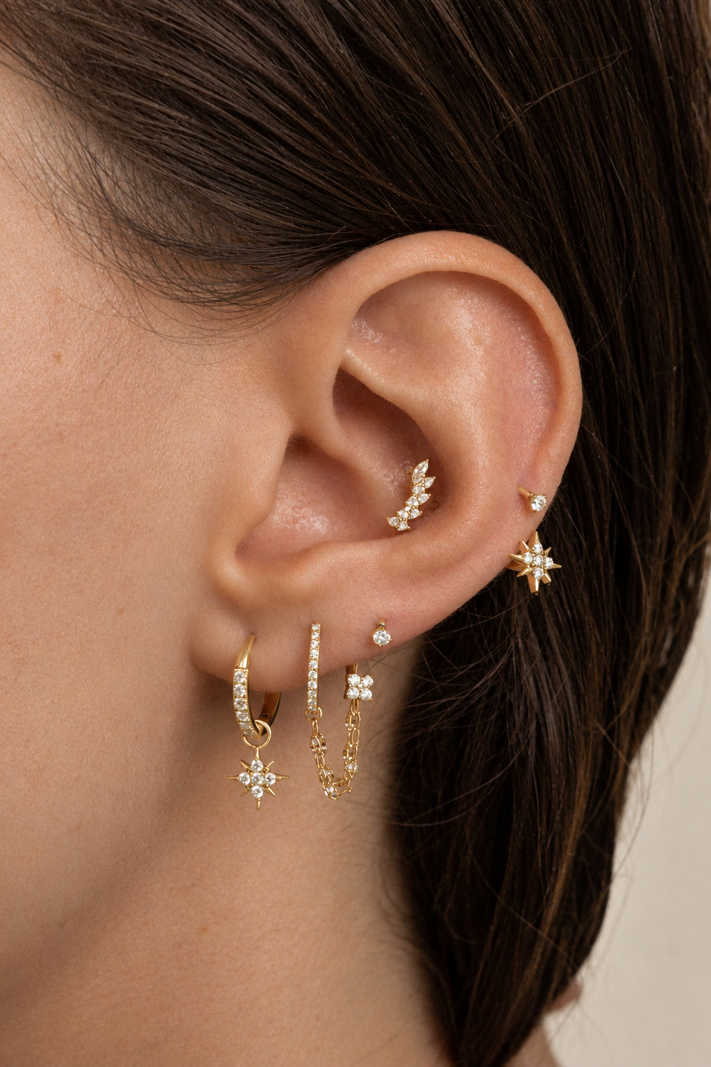 Composition portée avec pierres marquise au conch et pendentifs étoiles dorés au lobe.