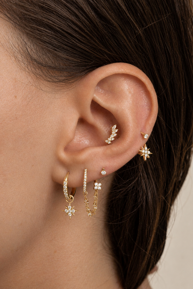 Composition portée avec pierres marquise au conch et pendentifs étoiles dorés au lobe.