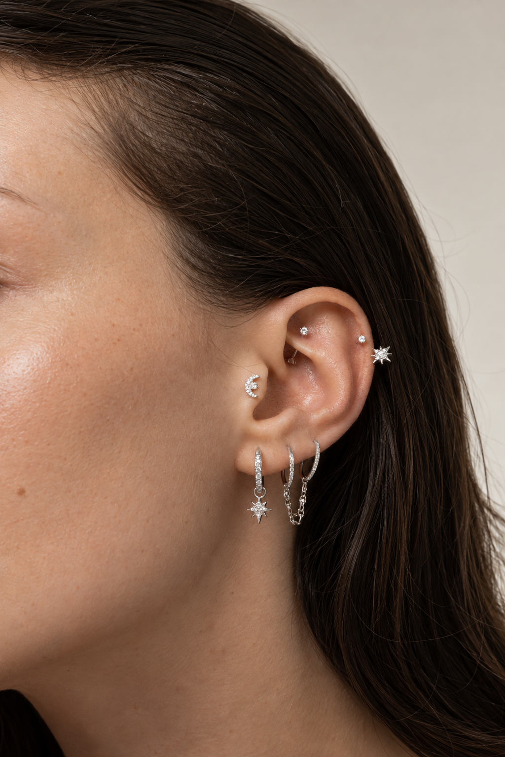 Silver-tone Constellation ear stack being worn, with hoops with pendants and a moon at the conch.