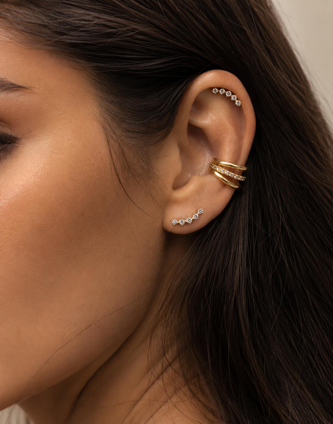 Ear stack being worn with a gold-tone Calypso ear cuff at the conch and stones aligned on the lobe.