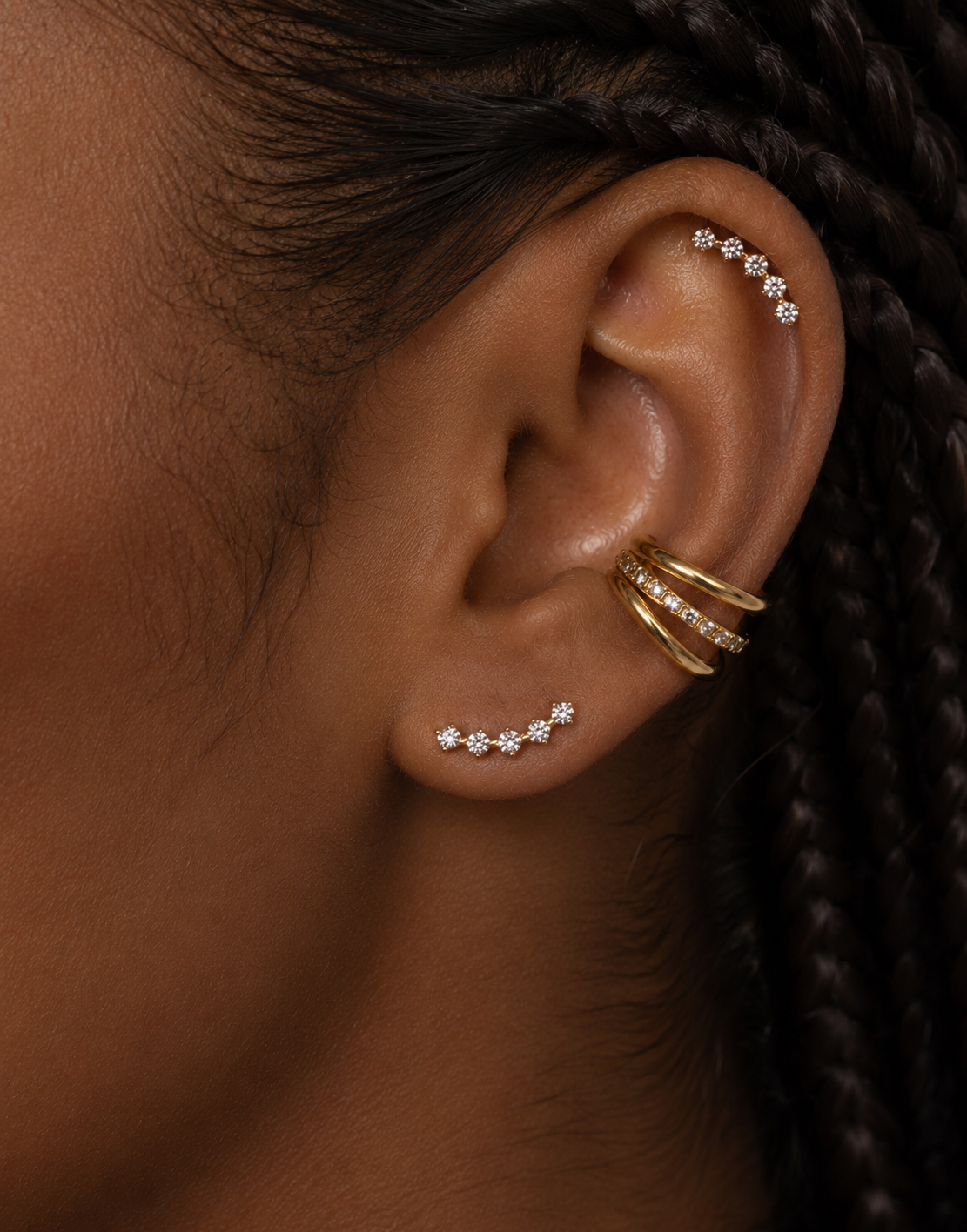 Ear cuff Calypso doré porté au conch avec lignes de pierres au lobe et à l’hélix.